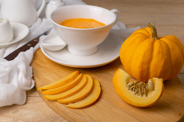Pumpkin sliced on wooden board with soup on the wooden table.