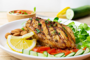 Top view of Fresh salad with chicken breast in white dish on wooden table, Almond,Sunflower seedling,Cucumber,Tomato,Lemon.