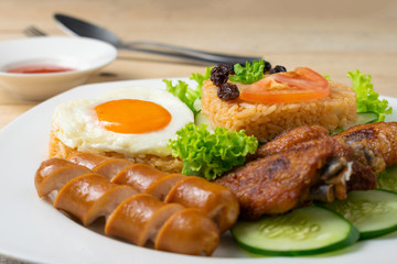 American fried rice with cucumber and lettuce in white dish on wooden table.