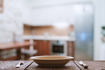 empty plate with fork and knife on wooden table