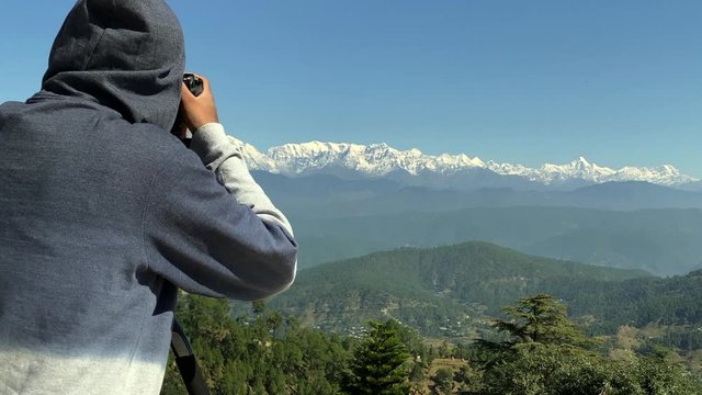 Indian Male photographer capturing a panoramic view of the Himalayan range