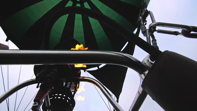 Adventure on hot air balloon watermelon. Burner directing flame into envelope. The aircraft fly in morning blue sky due to hot air. Hot air burning gas fire to air balloon or aerostat during flight.