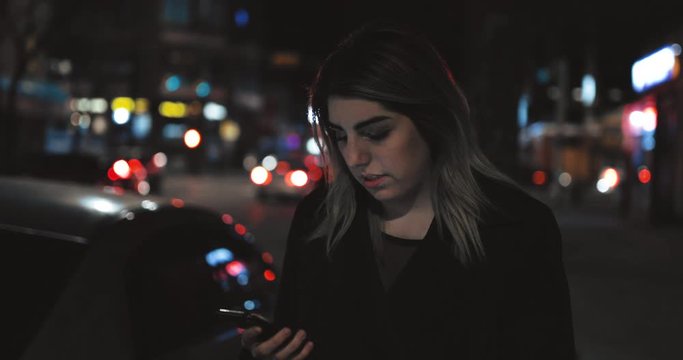 Young Women looks Annoyed While Looking at Cellphone in a Beautiful City Street at Night 4k Slow Motion Cinematic