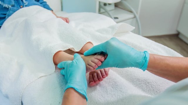 Professional reflexologist gently rubs cream into baby foot by massage