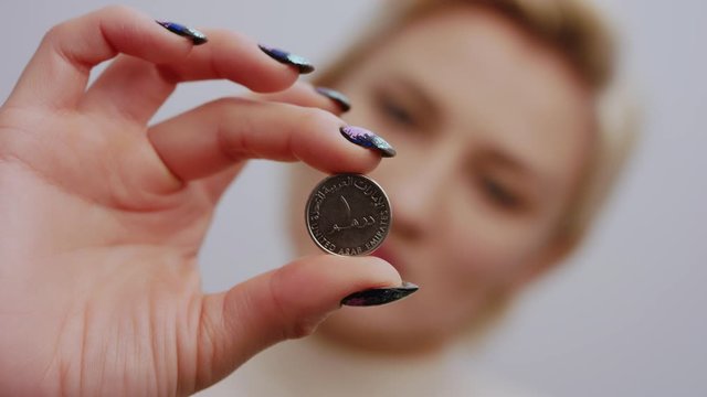 Woman's hand holding one United Arab Emirates dirham in her hand. Risky currency concept.