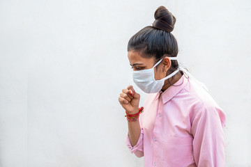 Indian girl wearing breathing mask coughing as the result of spreading Coronavirus, originating in...