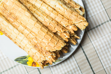 Hot waffles rolled into straw in plate on kitchen table.