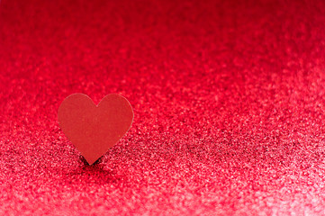 Obraz premium Red heart on a red shiny background with bokeh. Monochrome photography.