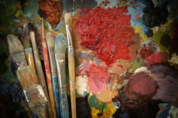 artist's old real brushes on a dark contrasting colorful palette. top view. copy space