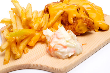 A close up of cheesy chicken breast set with fries and coleslaw insight 