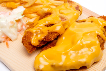 A close up of cheesy chicken breast set with fries and coleslaw insight 