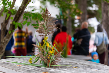 Closeup of yellow flowers blooming by wooden textured table against people listening fairytale story in background at park during event