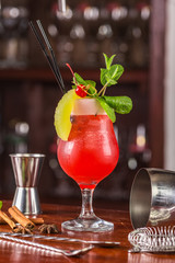 sex on the beach coctail on a wooden stand. Bar accessories: shaker, spoon, spices on a wooden stand