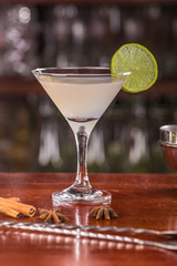 Margarita coctail on a wooden stand. Bar accessories: shaker, spoon, spices on a wooden stand