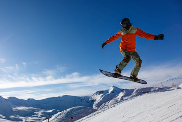 Snowboarder jumps in snow park in the snowy mountains
