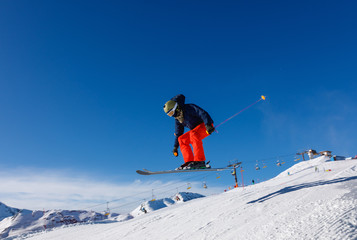 Fototapeta na wymiar Skier jumps in snow park against the blue sky in Livigno ski resort, Italy