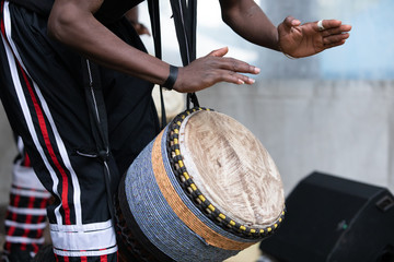 Closeup of african man wearing stripped pant and performing traditional african djembe drums while standing during world and spoken word festival