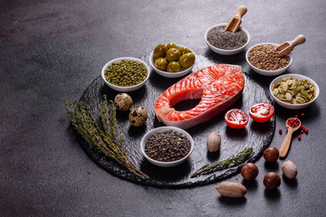 Raw trout red fish steak served with herbs and lemon and olive oil on a dark background