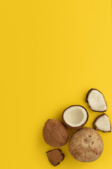 Ripe coconuts on yellow background. Coconuts in different forms in the corner of the background. Top View. Copy Space. Minimal summer concept