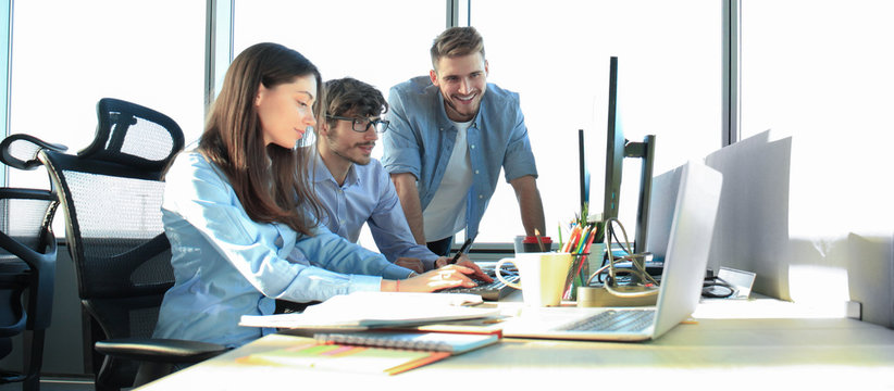 Young colleagues in smart casual wear working while spending time in the office.