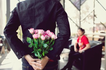 Man holding pink bouquet of roses on back, Surprise special time.