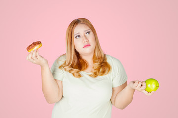 Overweight woman holds donuts and apple fruit