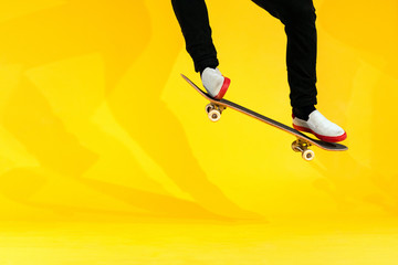 Skateboarder performing skateboard trick - ollie on concrete. Studio shot of olympic athlete practicing jump on yellow background, preparing for competition. Extreme sport, youth culture