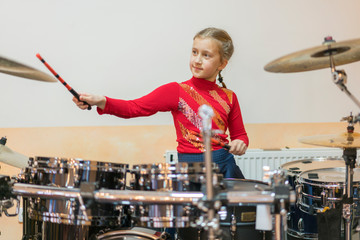 Teen girl playing the drums. Teen girls are having fun playing drum sets in music class. Girl in...