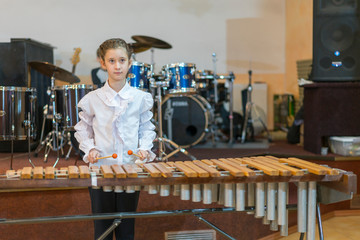 Teenager girl in a white shirt boy playing the marimba