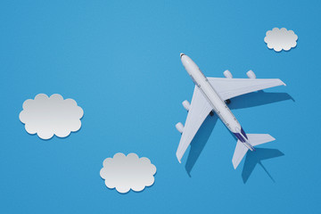 Miniature toy airplane on colorful paper background. Flat lay design of travel concept with plane and clouds on blue sky.