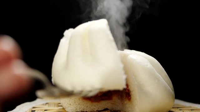 Hot steamed bun with steam in slow motion on black background