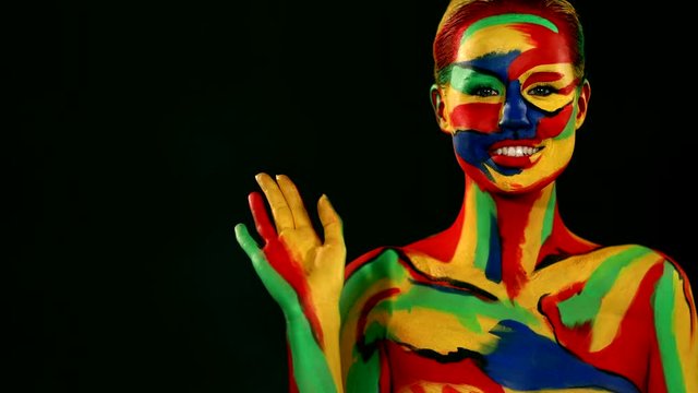 Woman with color face art and body paint. Girl with bright colorful makeup and bodyart pointing to looking right