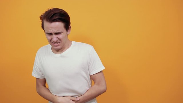 Stomach pains stomach problems white T-shirt young male on yellow background