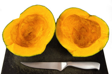 Buttercup squash cut in half on cutting board with knife. Kabocha squash, turban squash or  Cucurbita maxima. Orange sweet flesh, high on vitamine a and fiber. Bake, cook, steam or pressure cook. 