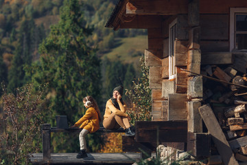 Fototapeta premium mother and daughter work on laptop outside on terrace in autumn.