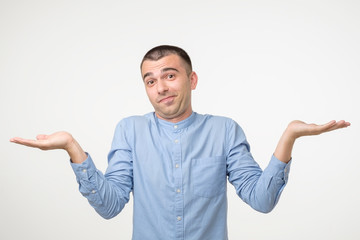 Upset young hispanic man shrugging shoulders as he does not know right solution.