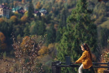 Fototapeta na wymiar cute little girl uses laptop outside sitting on terrace in mountains in autumn.