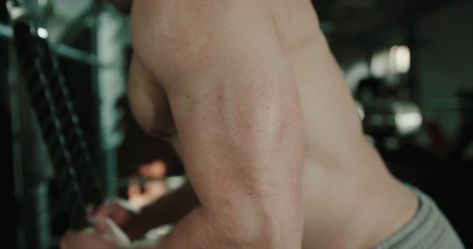 Muscular bodybuilder man is training his chest and his biceps mucles on machine