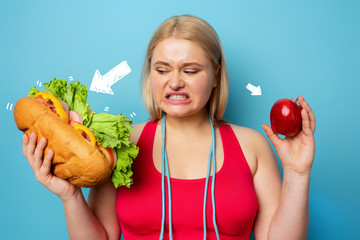 Fat girl does gym and want to eat a sandwich. Concept of indecision and doubt