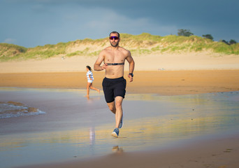 Fitness sports man using heart rate monitor running on beach