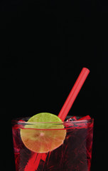 red berry soda with lime on black background