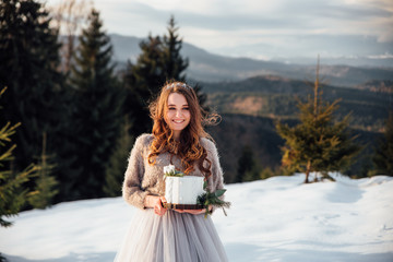 Attractive bride with wedding cake in the winter mountains