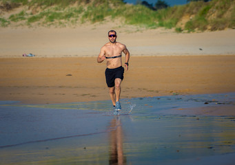 Fitness sports man using heart rate monitor running on beach
