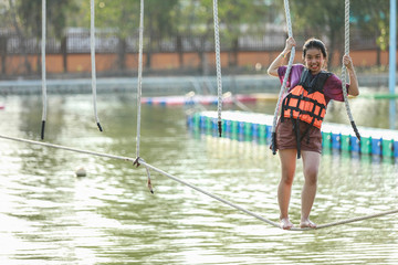 Young teenage girl walking on tight rope over the water