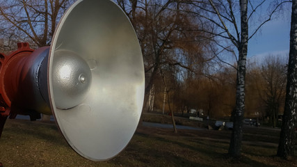 Silver painted loudspeaker on blurry trees background