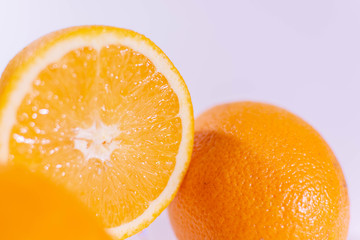 Halved orange near a whole orange on a white background
