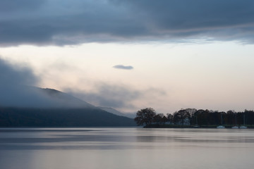 Stuning Autumn Fall sunrise landscape over Coniston Water with mist and wispy clouds