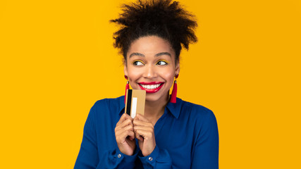 Black woman holding credit card and looking up - obrazy, fototapety, plakaty