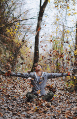 Man throwing autumn leaves in air