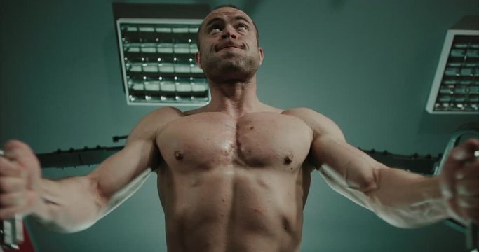 Close up of muscular man using weigth machine to workout his chest muscles